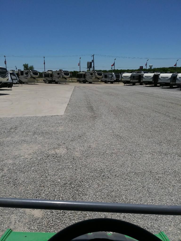 A row of trucks are parked in a gravel lot