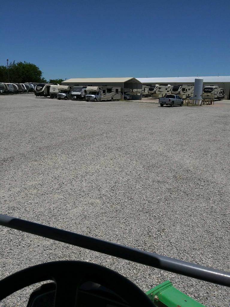 A gravel parking lot with a building in the background