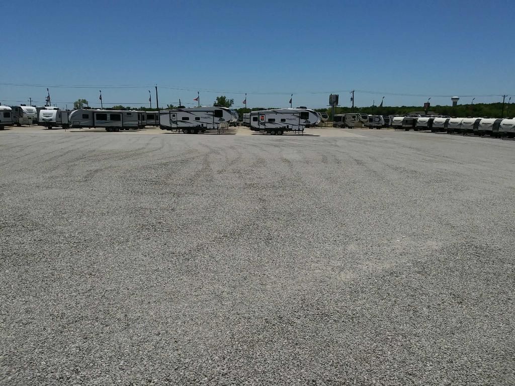 A lot of rvs are parked in a gravel lot