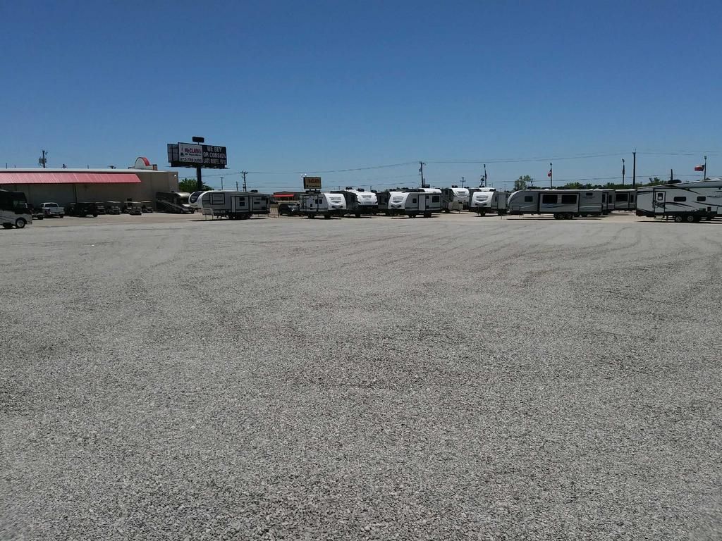 A row of trailers are parked in a gravel lot