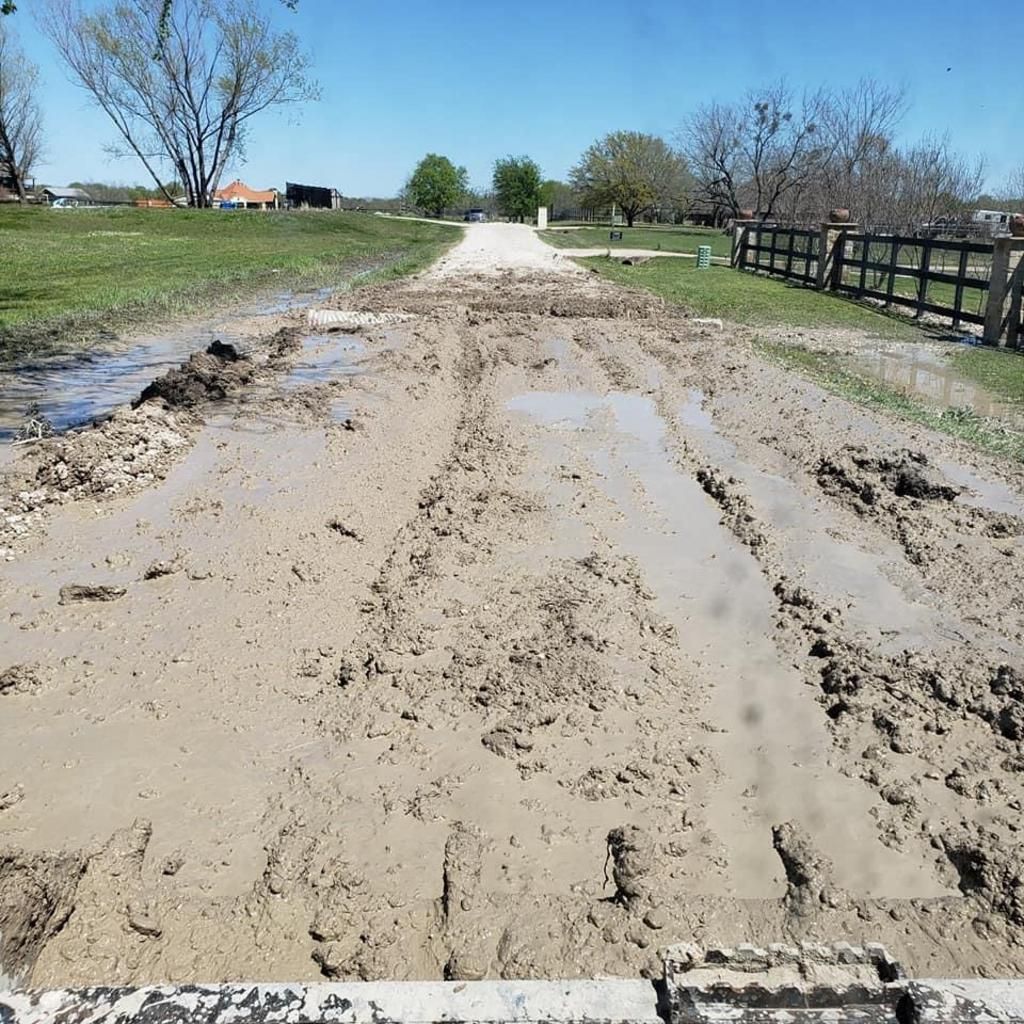 A muddy road with a fence in the background