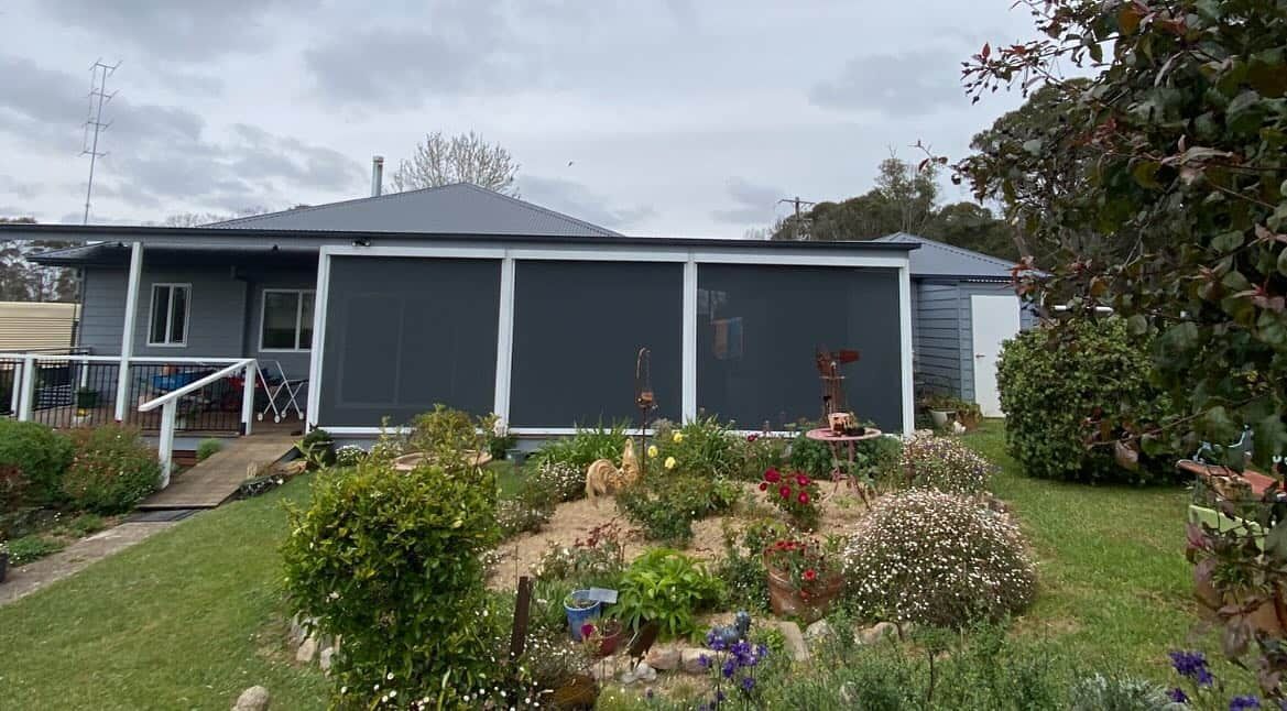 A House with A Screened in Porch and A Garden in Front of It — Douglass Blinds & Security Screens in Goulburn, NSW