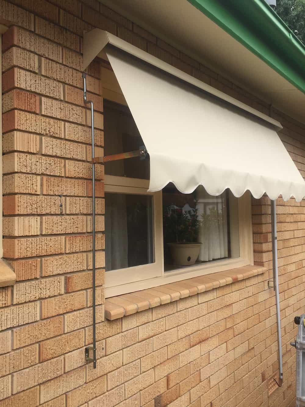 A Brick Building with A White Awning Over a Window — Douglass Blinds & Security Screens in Yass, NSW