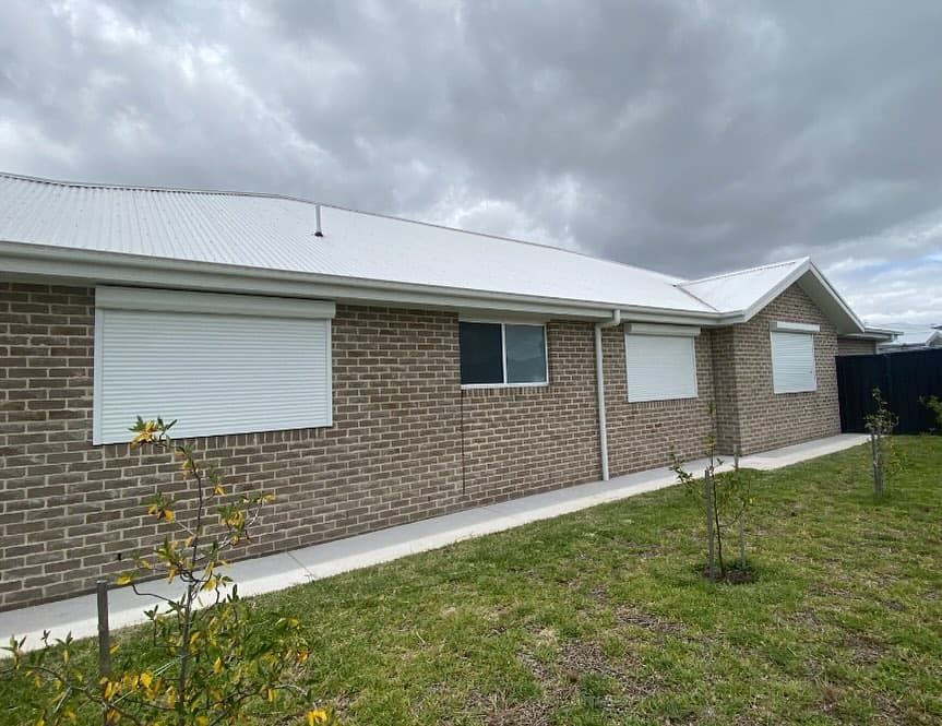 A Large Brick House with A Pergola on Top of It — Douglass Blinds & Security Screens in Crookwell, NSW