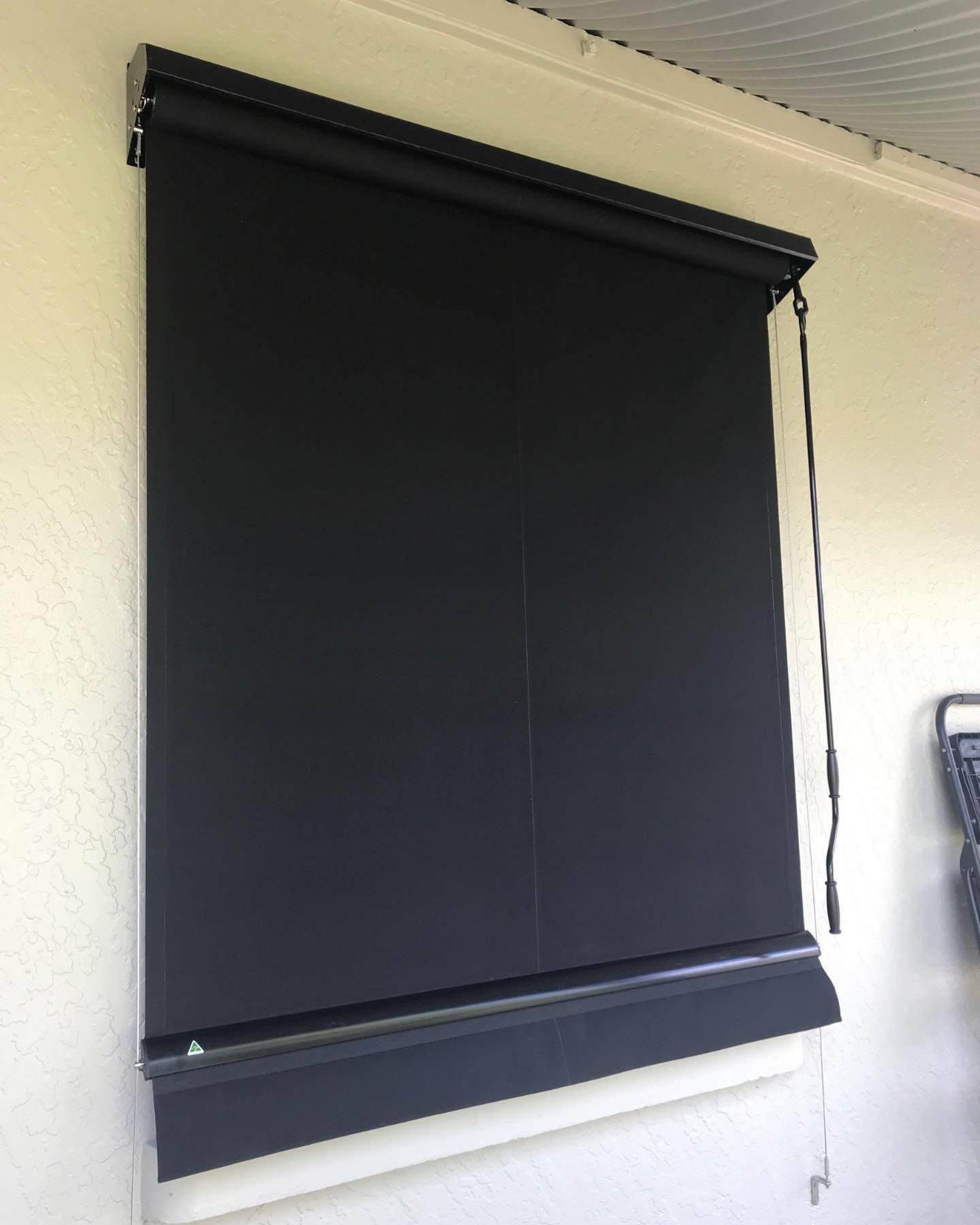 A Black Blind Is Hanging on A White Wall — Douglass Blinds & Security Screens in Goulburn, NSW
