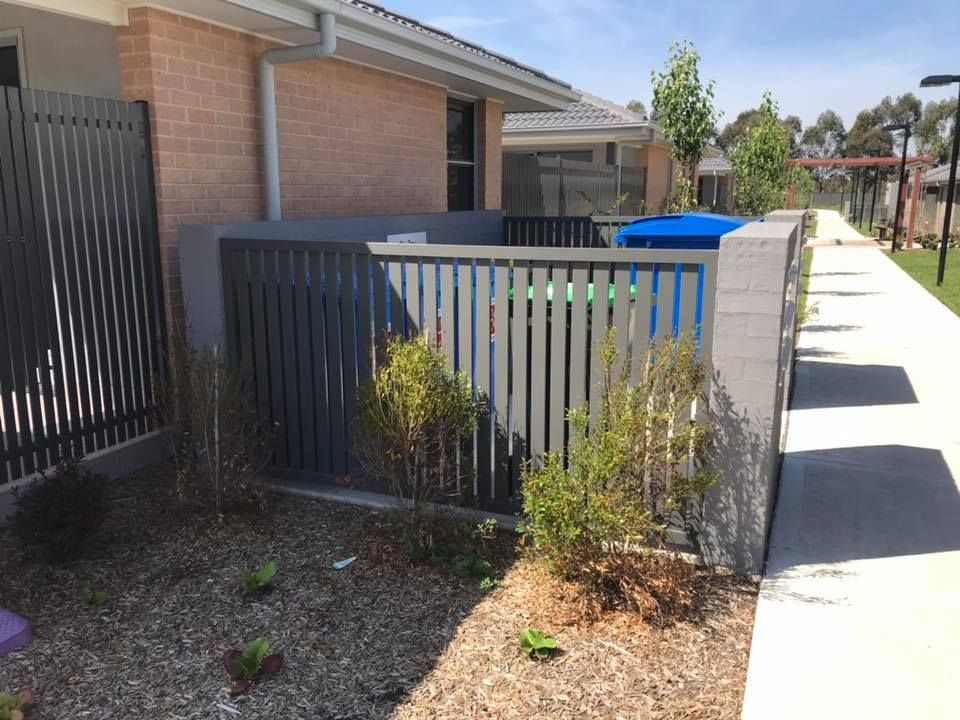 A Brick House with A Fence and A Blue Trash Can in Front of It — Douglass Blinds & Security Screens in Goulburn, NSW