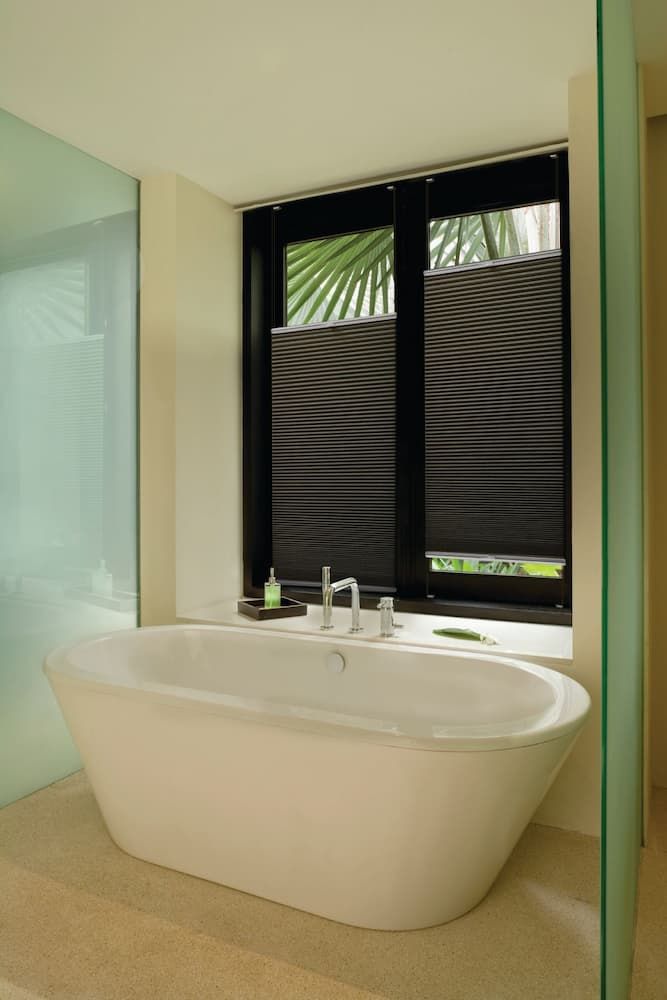 A Bathtub in a Bathroom Next to a Window With Blinds — Douglass Blinds & Security Screens in Goulburn, NSW