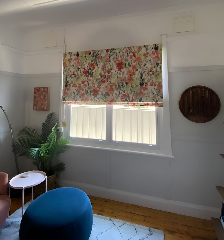 A Living Room With a Floral Roman Shade on the Window — Douglass Blinds & Security Screens in Goulburn, NSW