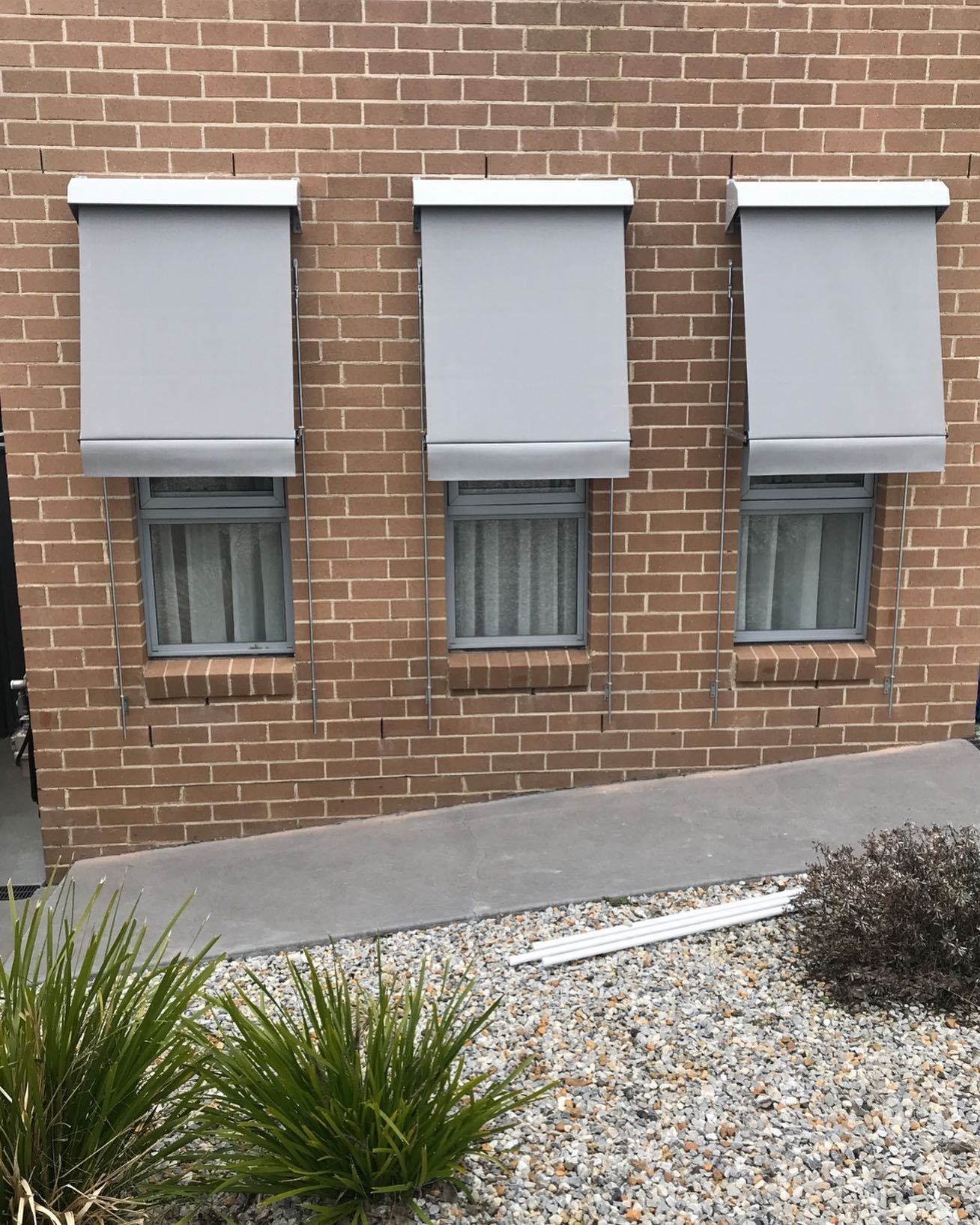 A Man Is Standing on A Sidewalk Next to A Building with Blinds on The Windows — Douglass Blinds & Security Screens in Taralga, NSW