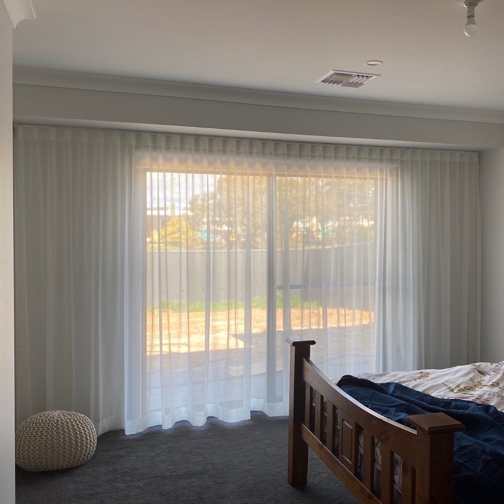 A Bedroom With a Bed and a Sliding Glass Door With White Curtains — Douglass Blinds & Security Screens in Goulburn, NSW