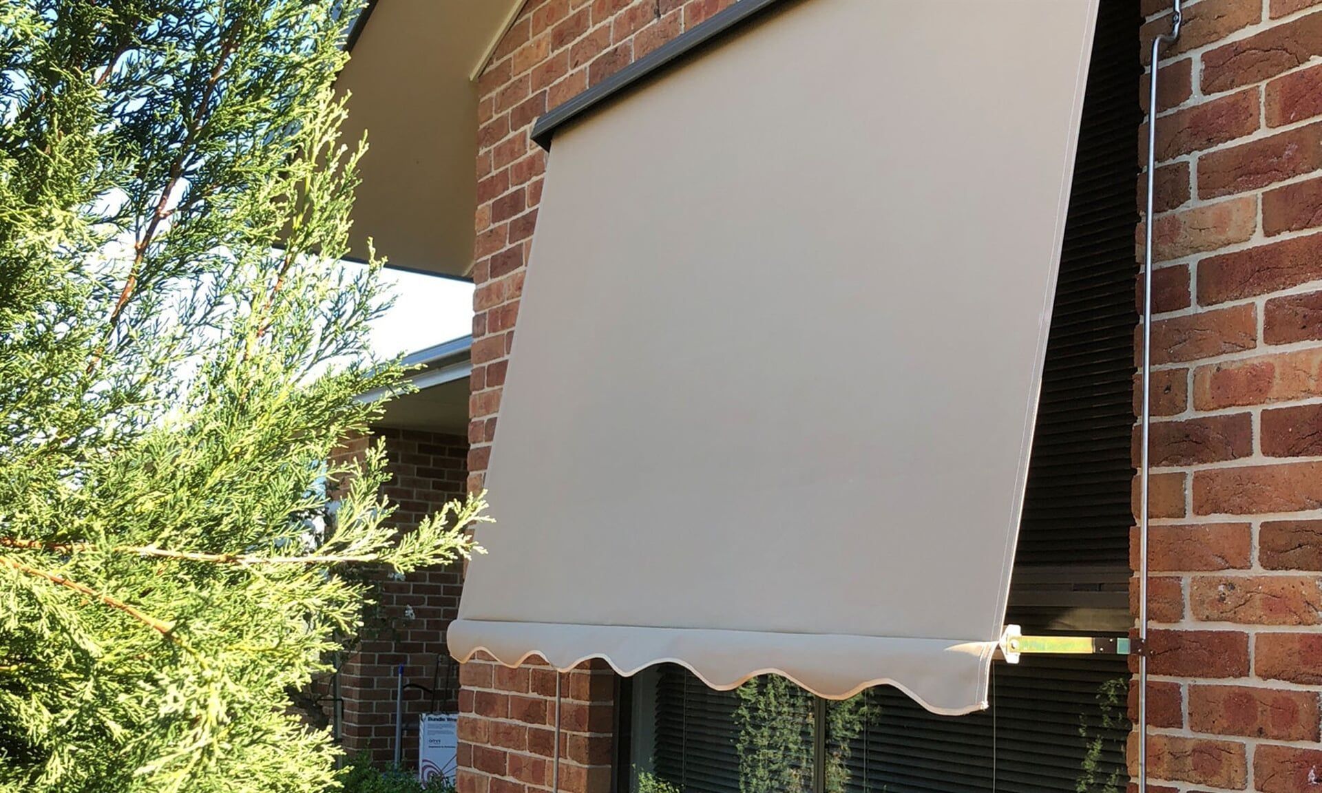 A Brick Building with A Awning on The Side of It — Douglass Blinds & Security Screens in Burradoo, NSW