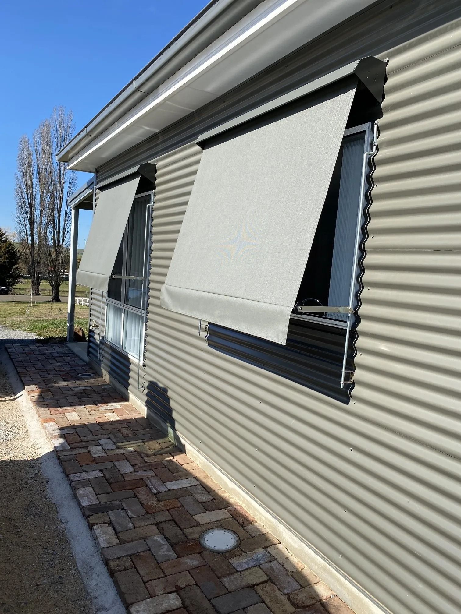 A House With a Brick Walkway and Awnings on the Windows — Douglass Blinds & Security Screens in Goulburn, NSW