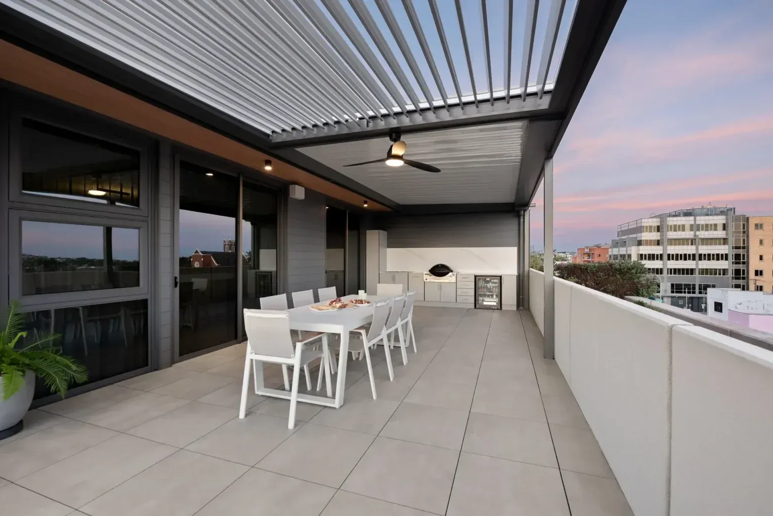 Rooftop patio with dining table, cooking area, and open view. Gray and white tones, evening sky. — Douglass Blinds & Security Screens in Goulburn, NSW