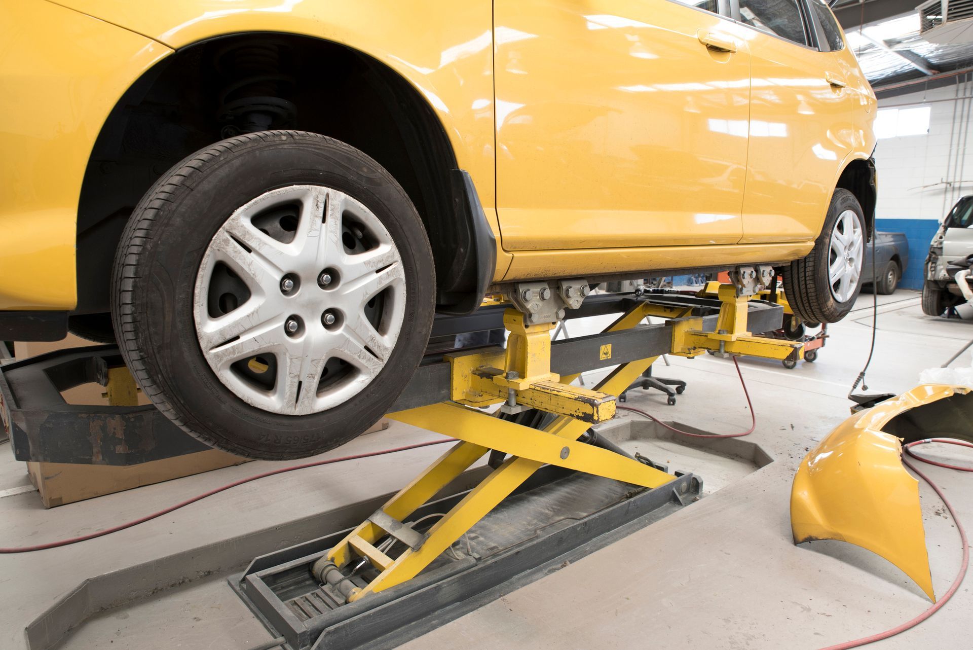 A yellow car is sitting on a yellow lift in a garage.