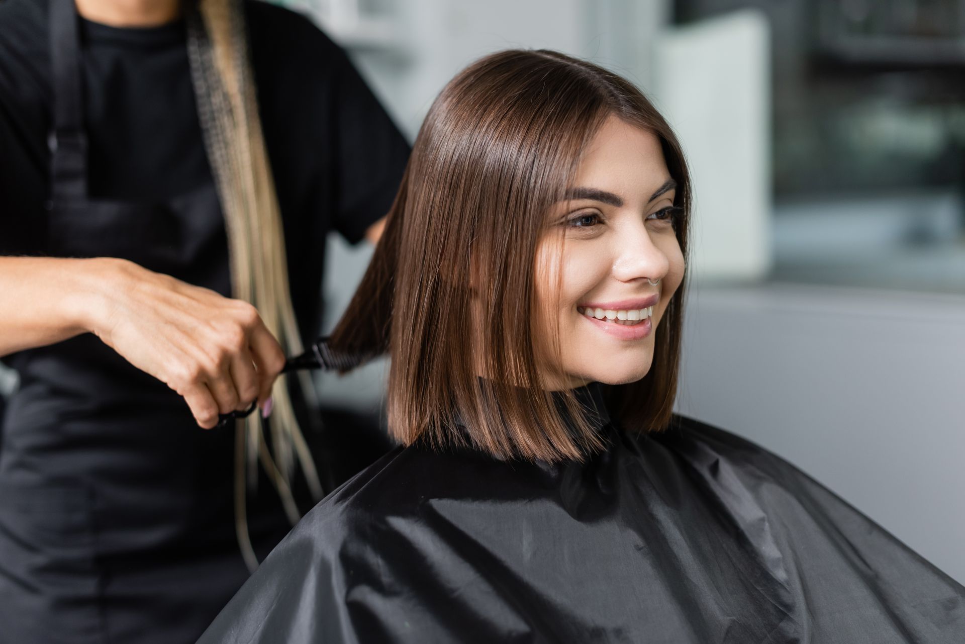 A woman is getting her hair cut by a hairdresser in a salon.