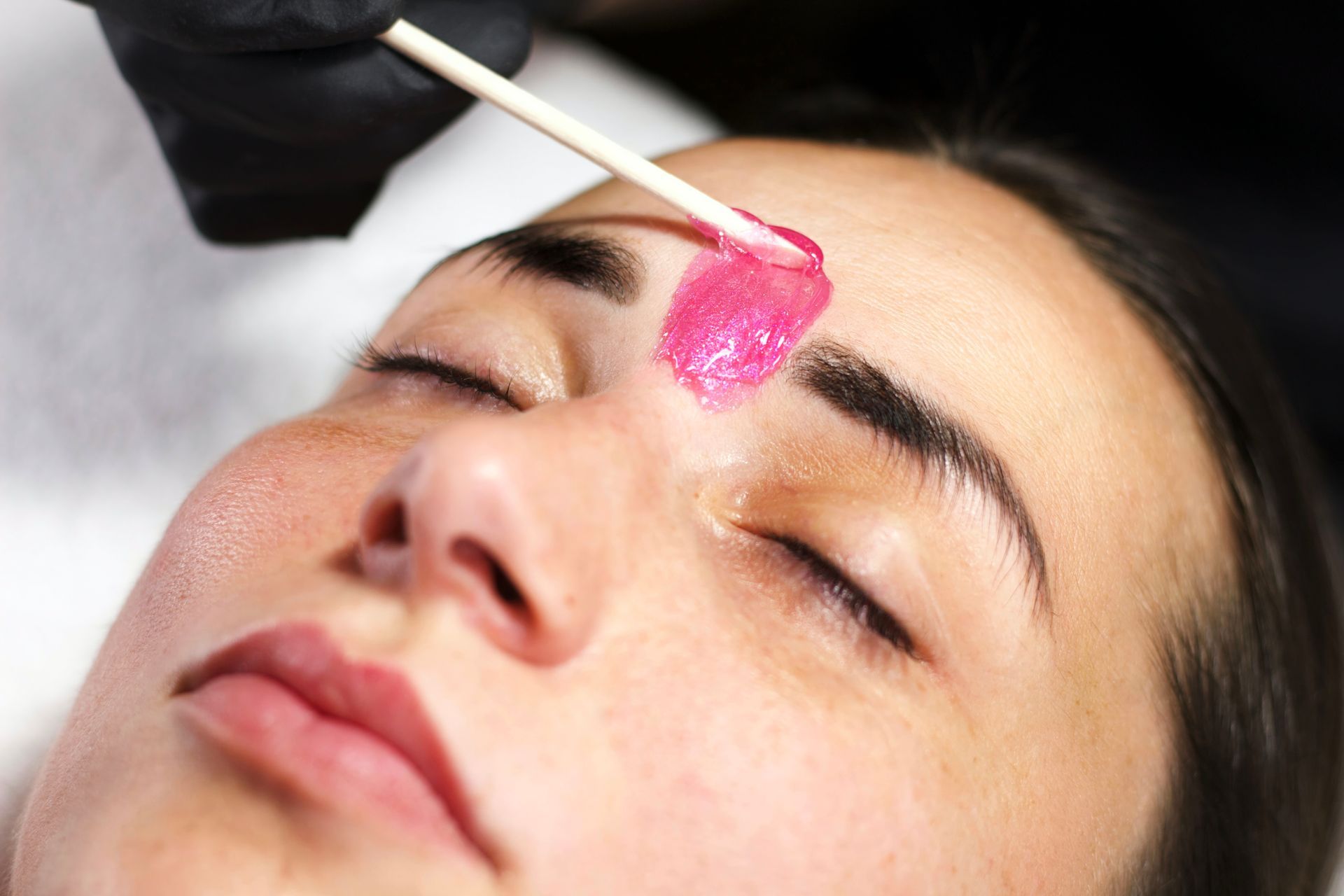 A woman is getting her eyebrows waxed in a beauty salon.
