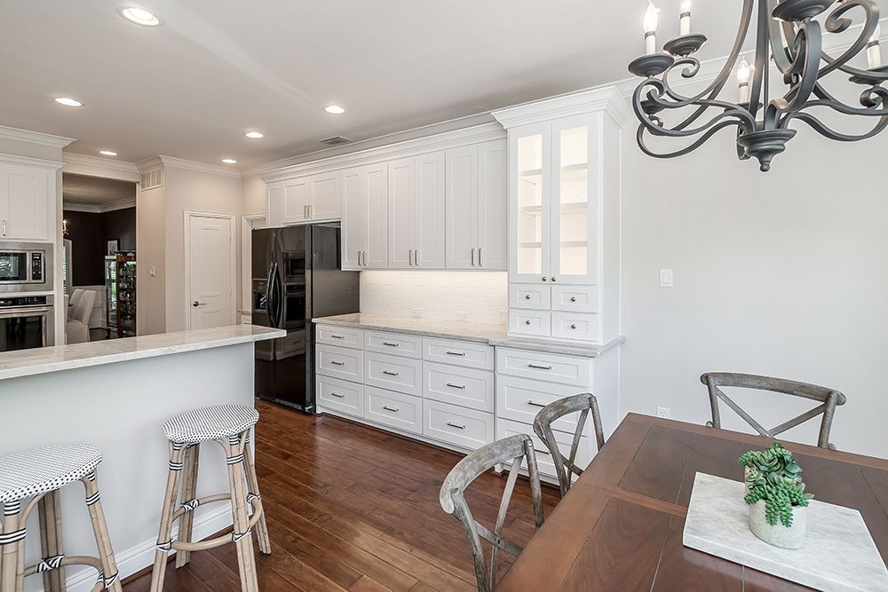 a kitchen with white cabinets and a black refrigerator