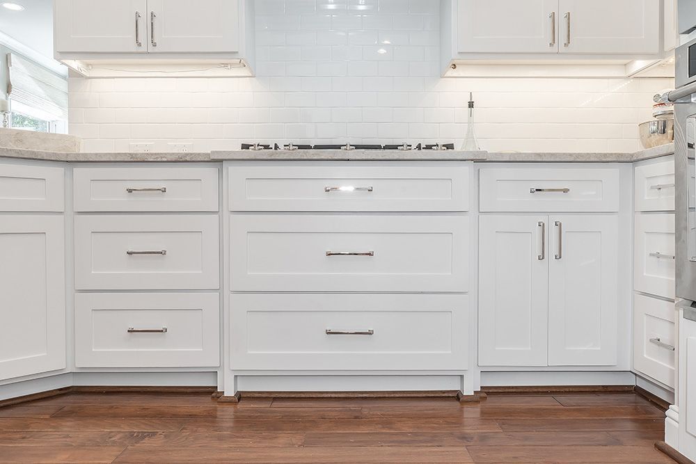 a kitchen with white cabinets and drawers and a stove top oven