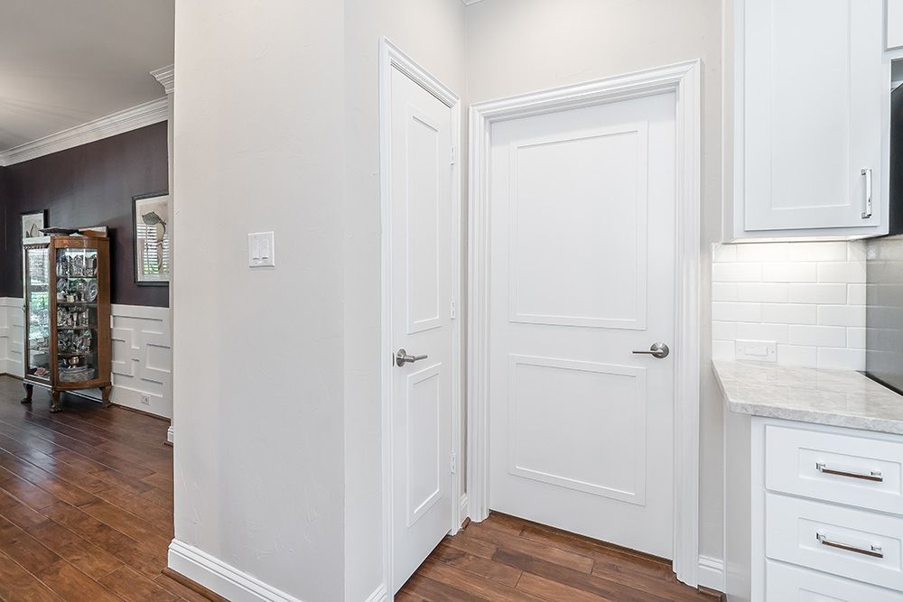 a hallway with two white doors leading to a kitchen