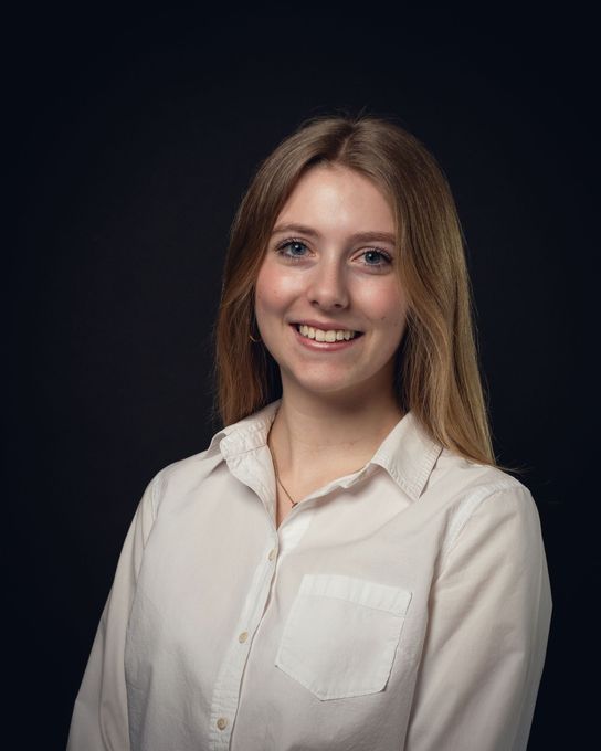 The woman is wearing a white shirt and smiling for the camera.