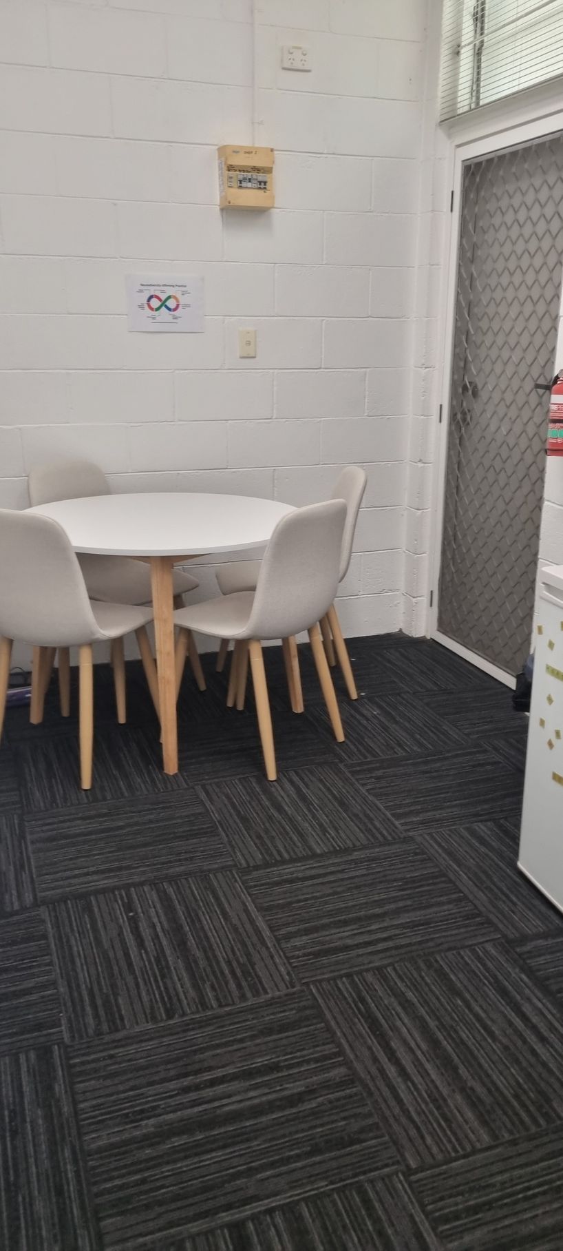 A small room with a table and chairs, gray carpet, and a door — RWM Cleaning in Deception Bay, QLD