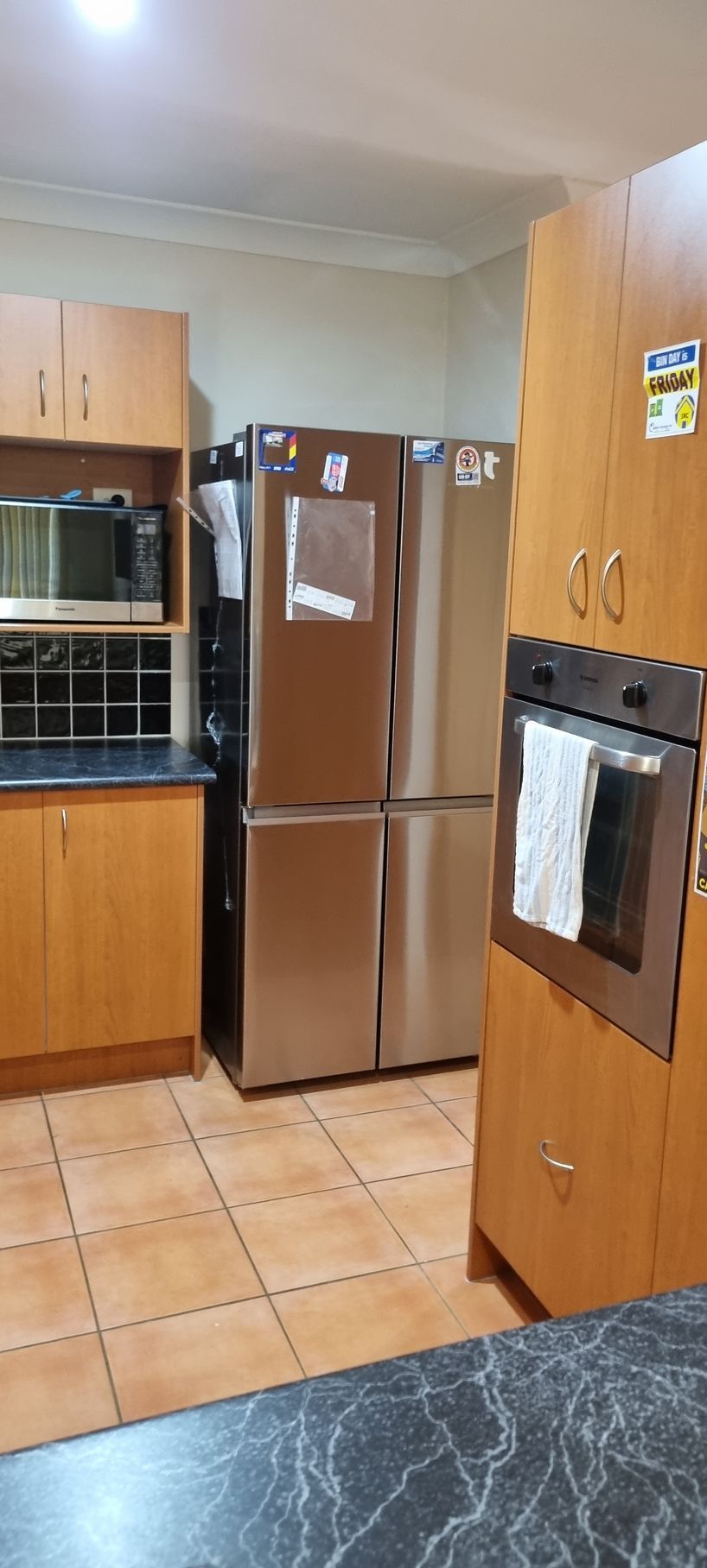 Kitchen with light brown cabinets, stainless steel refrigerator, and tiled floor — RWM Cleaning in Deception Bay, QLD