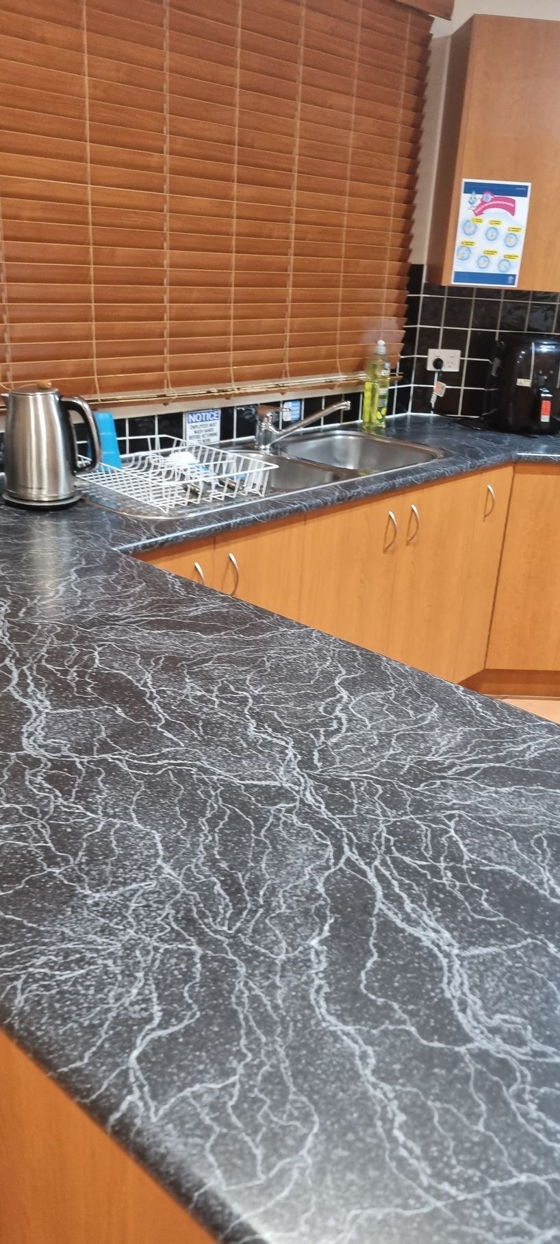Kitchen countertop with dark grey and white veining, wood cabinets, and a brown blinds — RWM Cleaning in Deception Bay, QLD