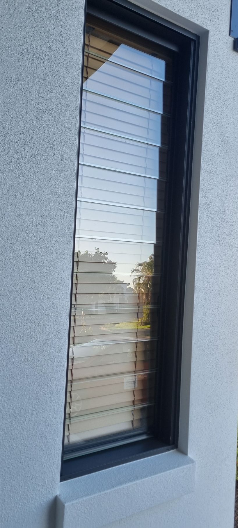 A rectangular window with horizontal blinds on a textured gray wall — RWM Cleaning in Deception Bay, QLD