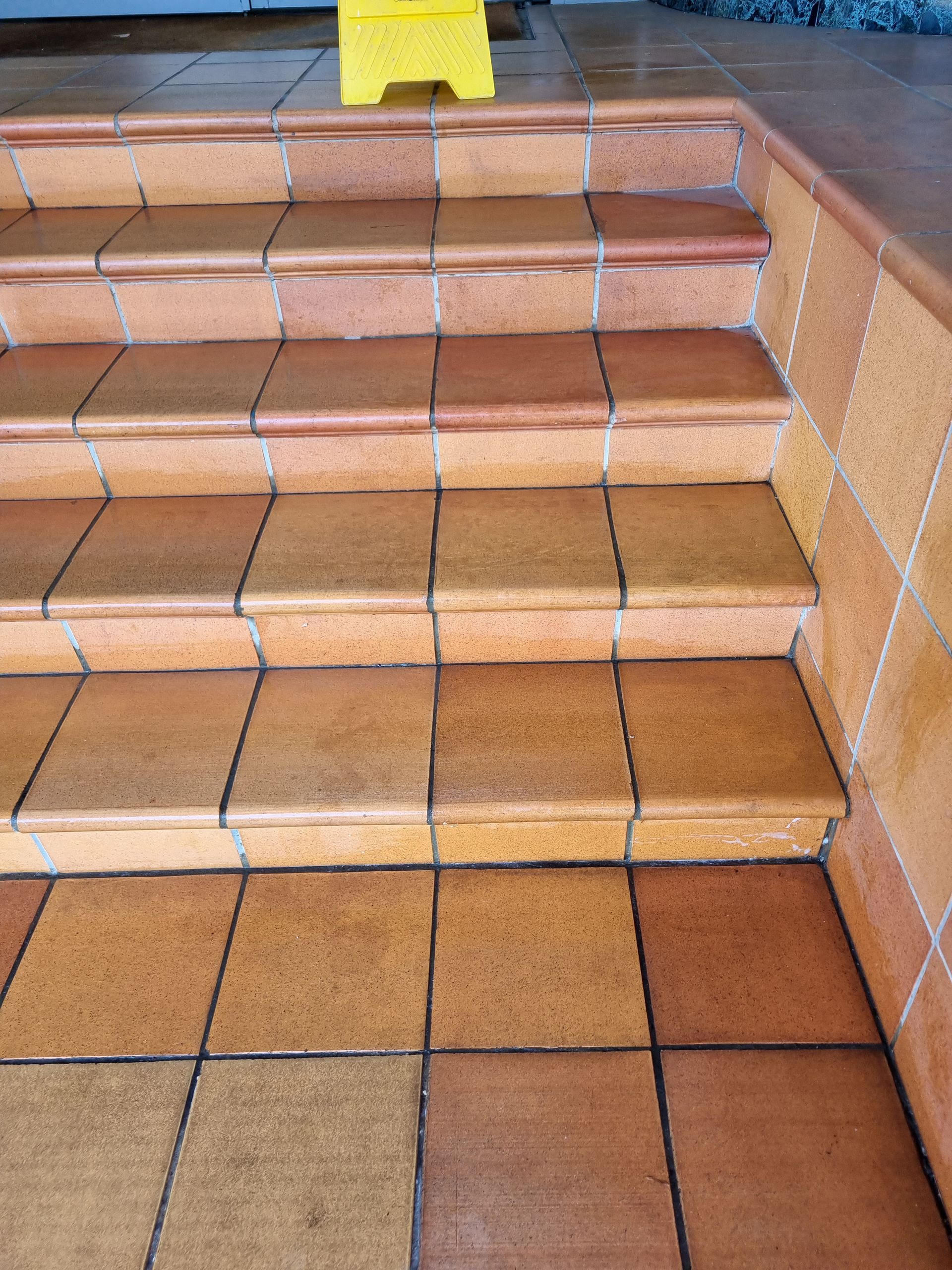 Orange Tiled Steps With a Yellow Caution Sign — RWM Cleaning in Deception Bay, QLD