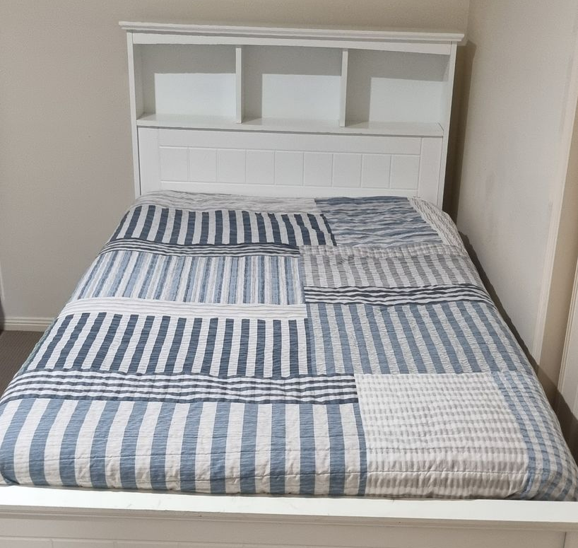 White bed with striped blue and white quilt and headboard with shelves — RWM Cleaning in Deception Bay, QLD