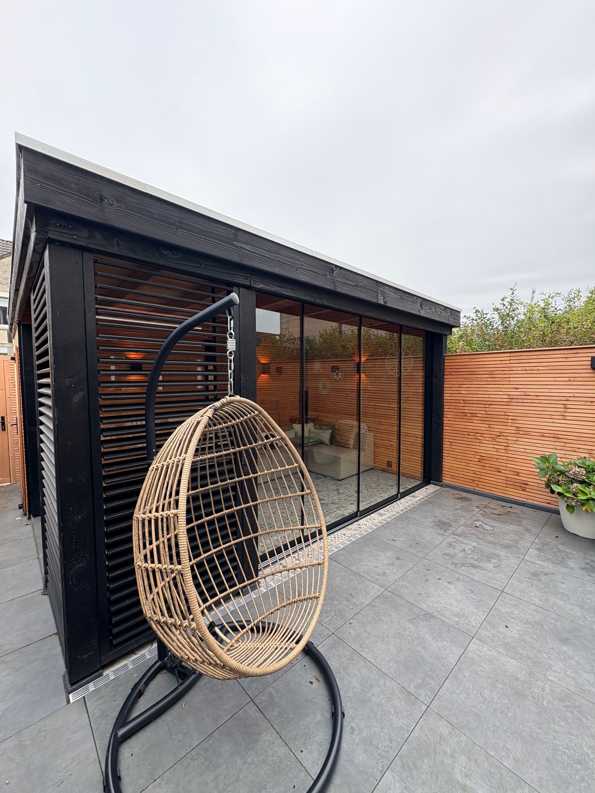 Moderne houten tuinlounge met plat dak, vlonder en zitgelegenheid buiten, 