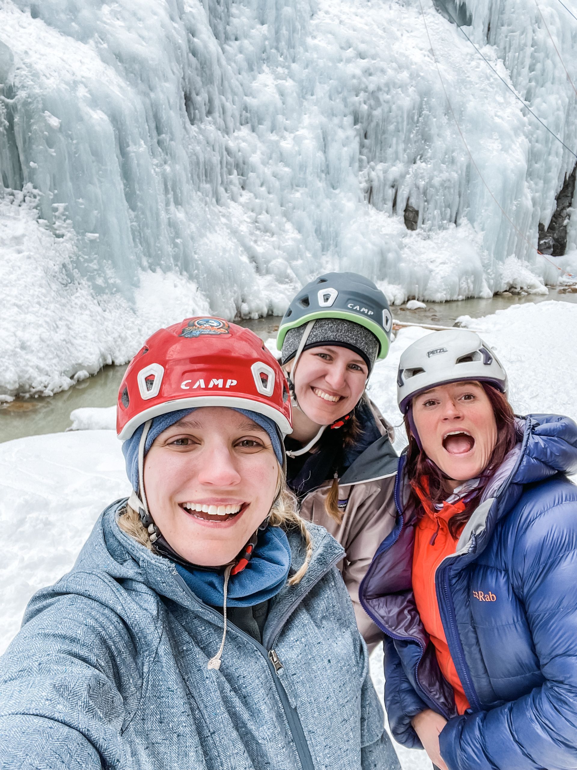 Ice climbers posing for a selfie in front of an ice climbing wall