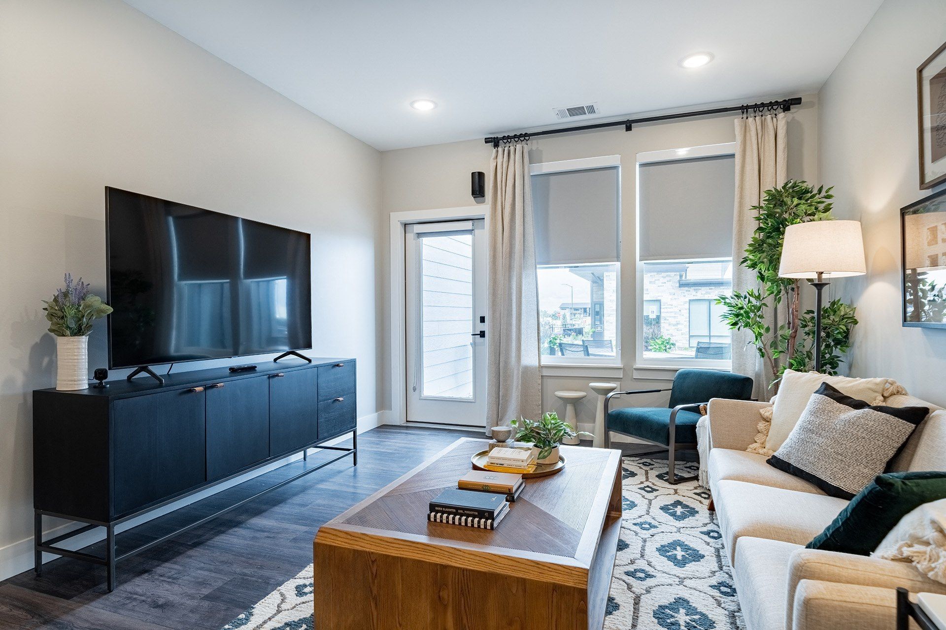 Living room with TV, black cabinet, sofa, rug, and window with blinds.
