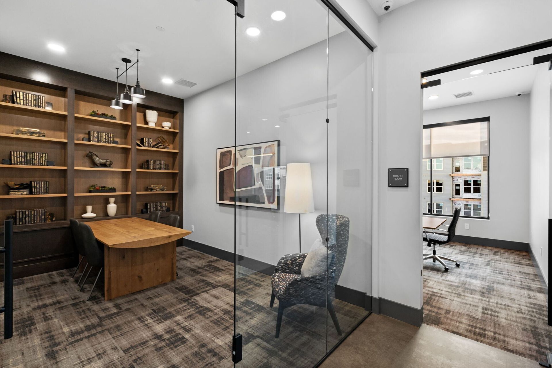 Outdoor patio with ping pong table, lounge areas, green chairs, fireplace, and apartment buildings under a partly cloudy sky.