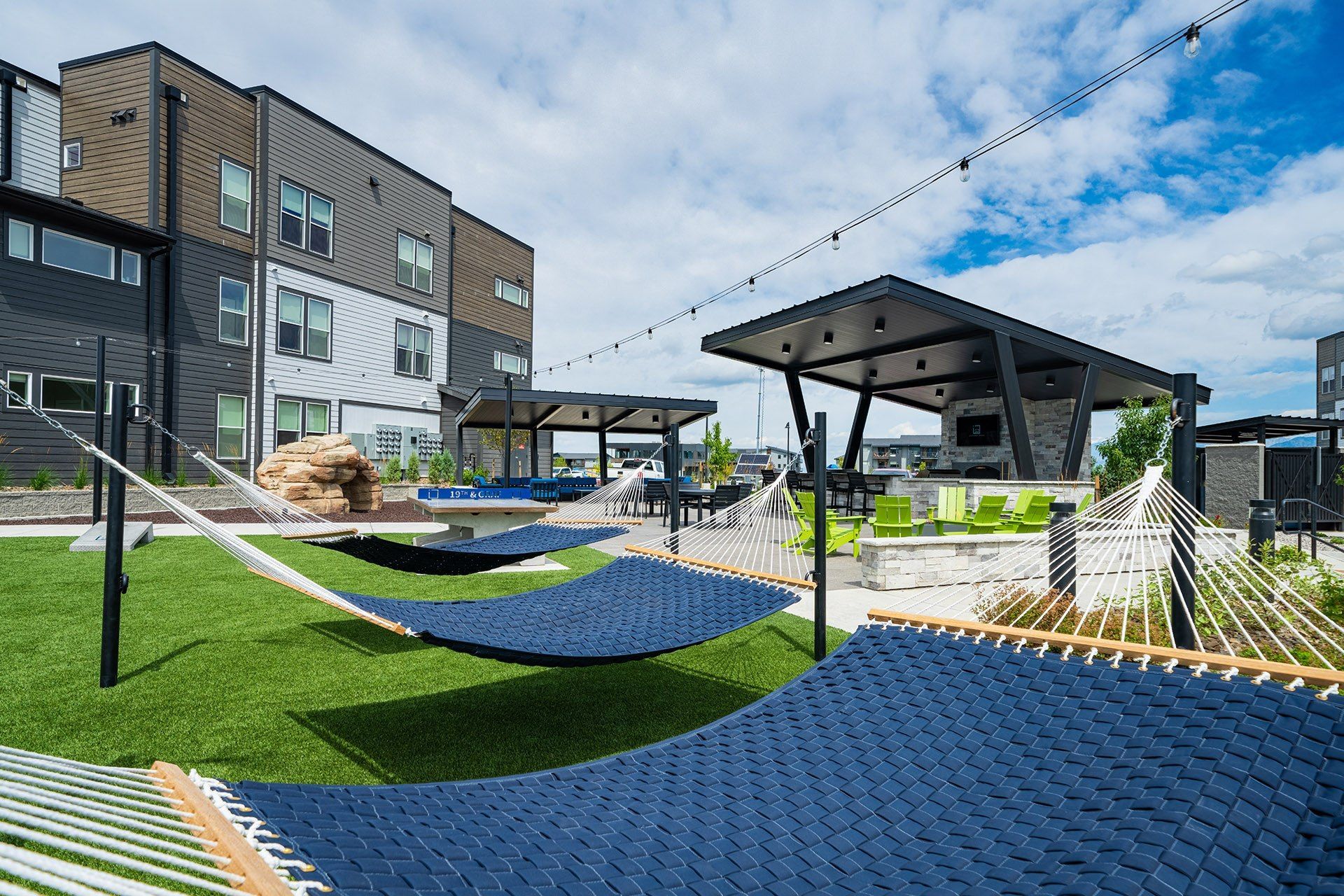 Outdoor patio with blue seating, fire pit, and apartment building in the background.
