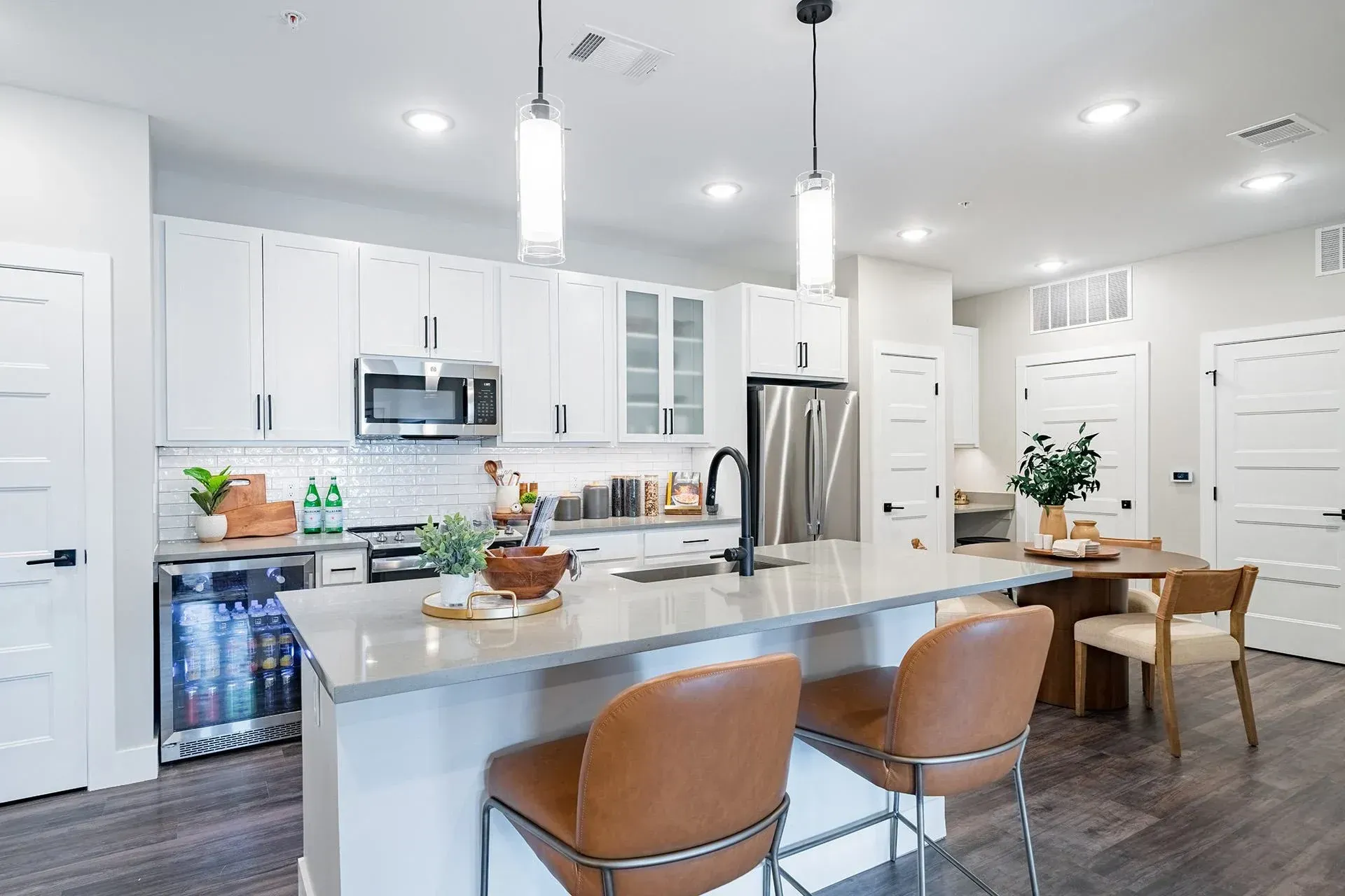 Modern kitchen with white cabinets, stainless steel appliances, and a gray island with bar stools.