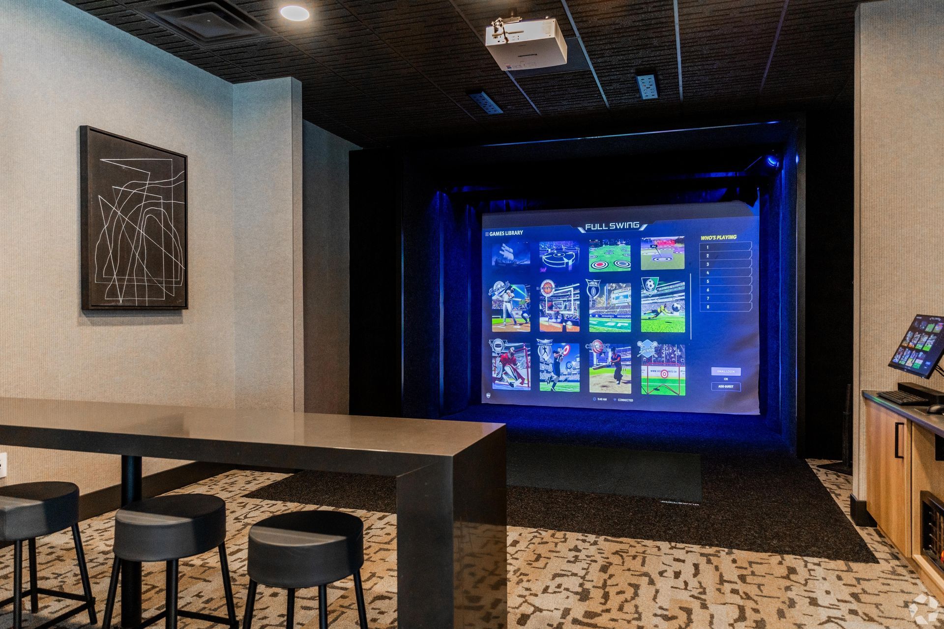 A recreational room with a large screen displaying sports, a bar table, stools, and a projector.