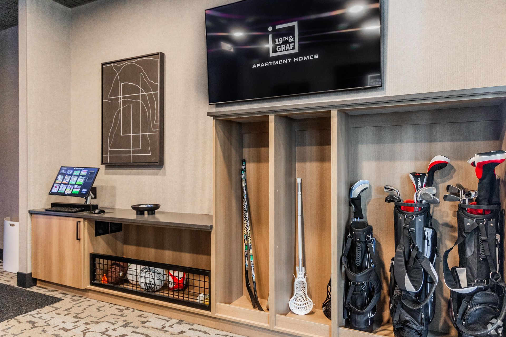 Golf club storage area with mounted TV, artwork, and a computer setup.