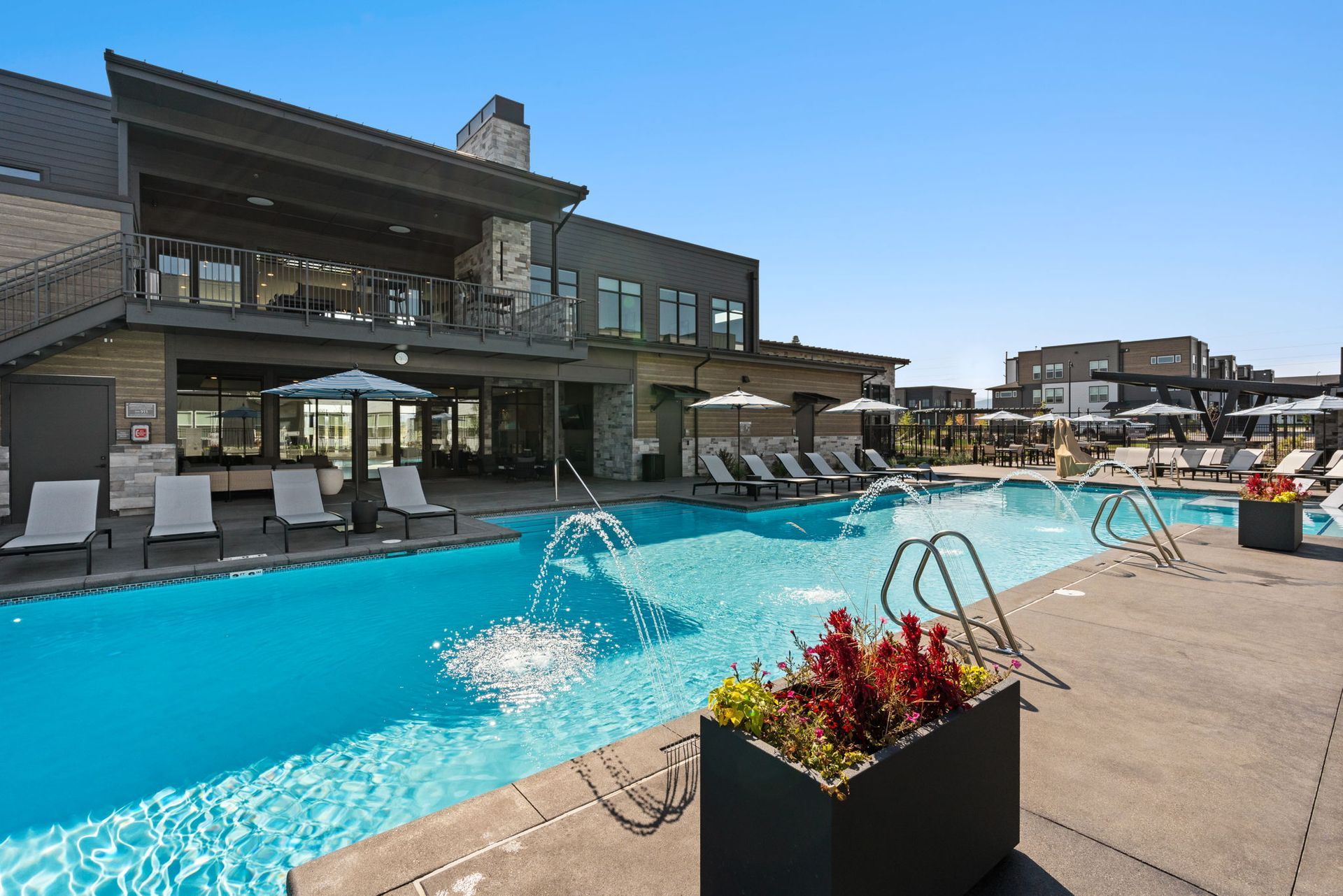 Swimming pool and lounge chairs at an apartment complex, with building in the background.