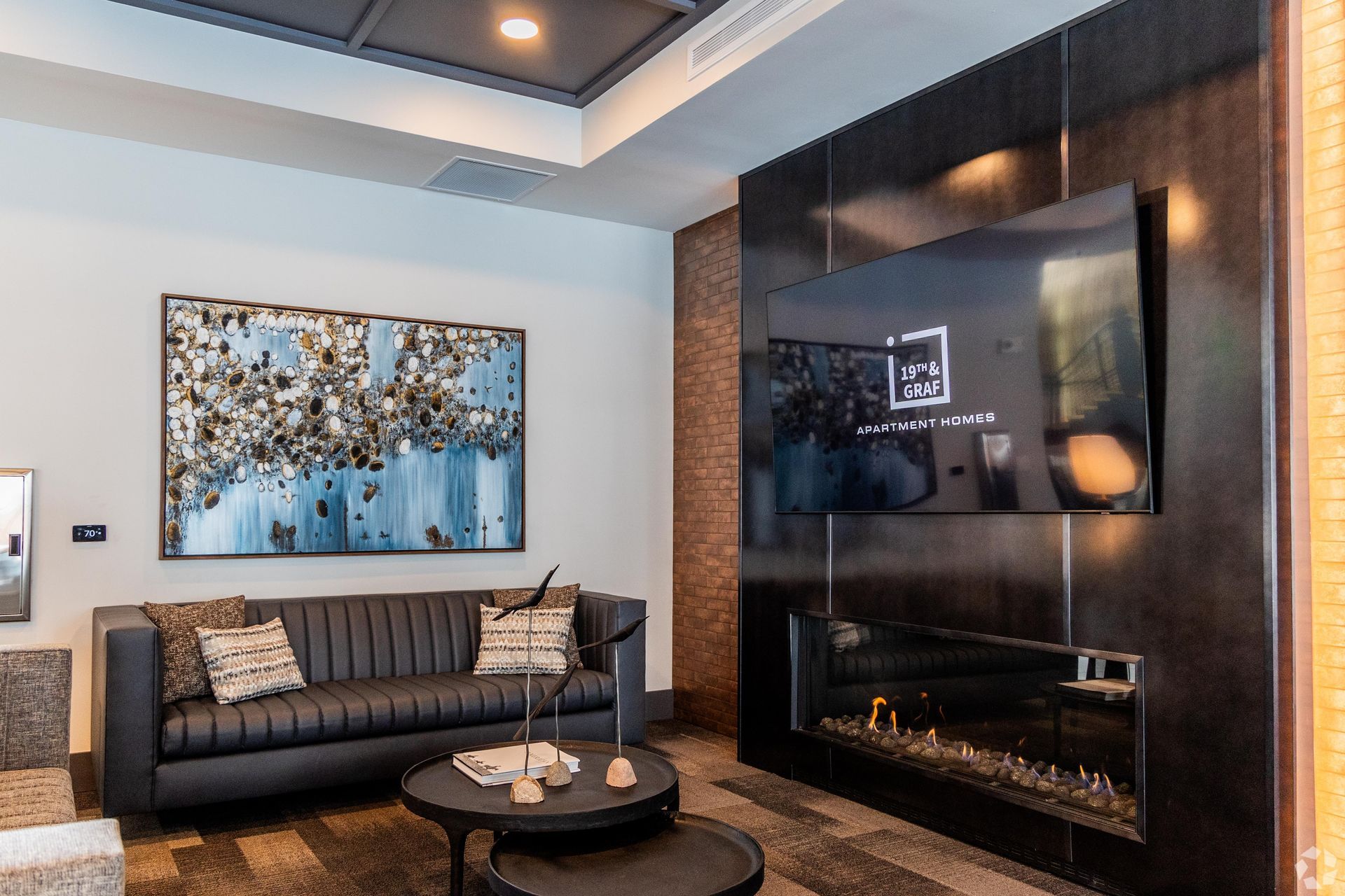 Lobby with a black sofa, modern fireplace, and large wall-mounted TV.