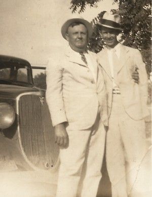 Two men in suits standing next to a car: Eugene Monroe Bartlett & his mentee Albert E. Brumley.