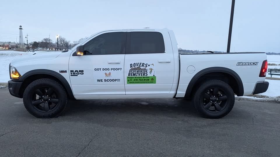 White RAM pickup truck with black wheels parked near a body of water at dusk.