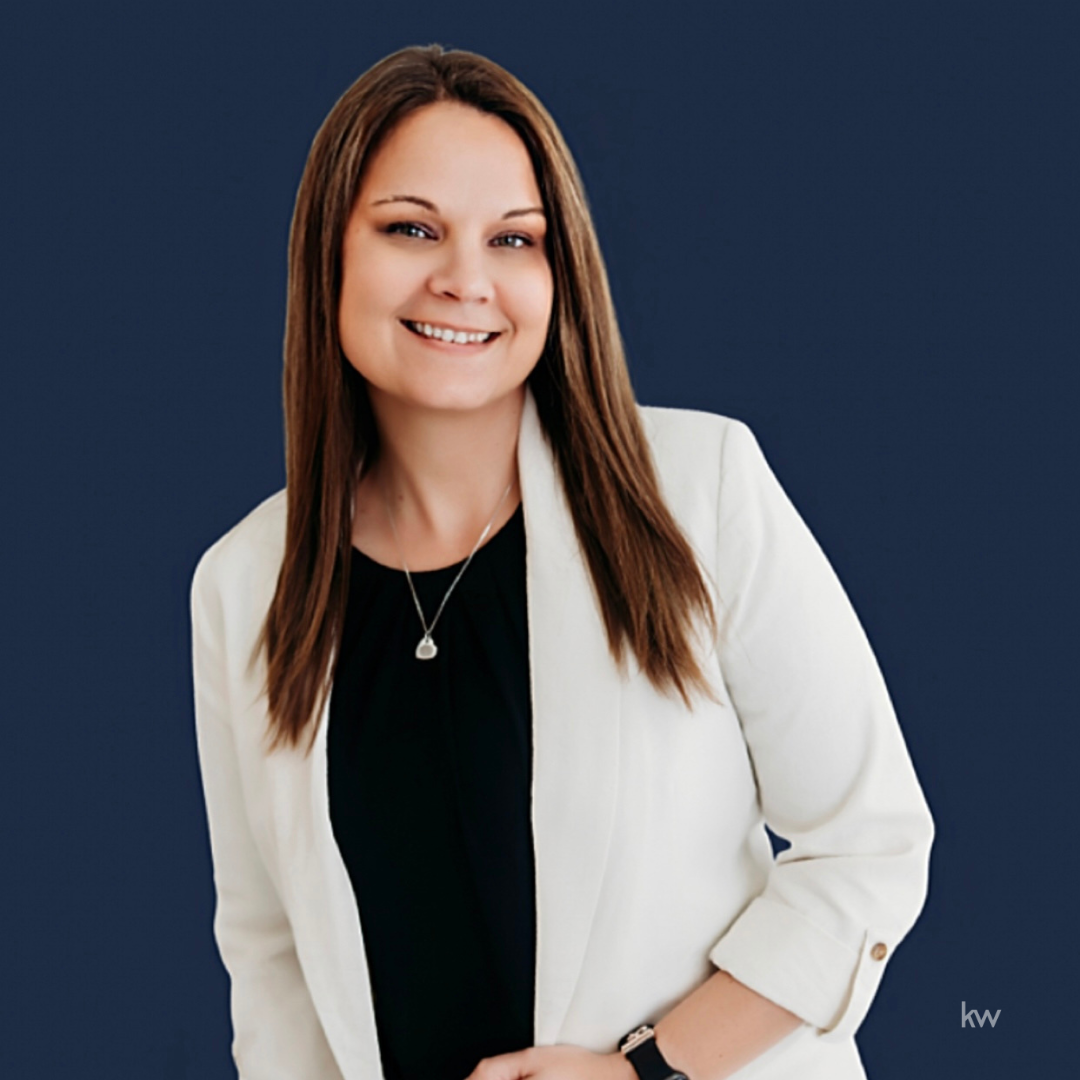 A woman is sitting at a desk with a laptop and a vase of flowers.