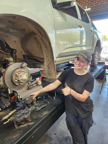 A Woman Is Standing Next To A Car In A Garage — Westend Auto Repairs in Bathurst, NSW