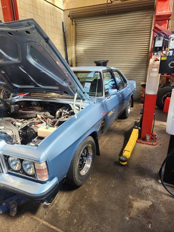 A Blue Car With The Hood Up Is Sitting On A Lift In A Garage — Westend Auto Repairs in Bathurst, NSW