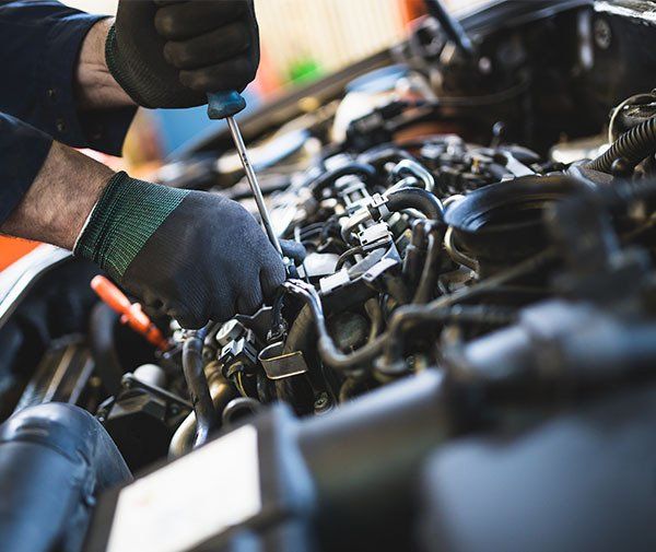 A Man Is Working On A Car Engine With A Screwdriver — Westend Auto Repairs in Bathurst, NSW