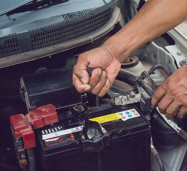 A Man Is Working On The Battery Of A Car — Westend Auto Repairs in Bathurst, NSW