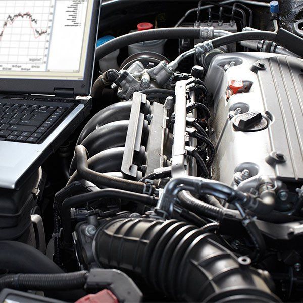 A Close Up Of A Car Engine Next To A Laptop — Westend Auto Repairs in Bathurst, NSW