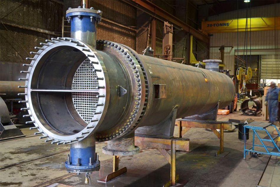 A large metal pipe is being built in a factory