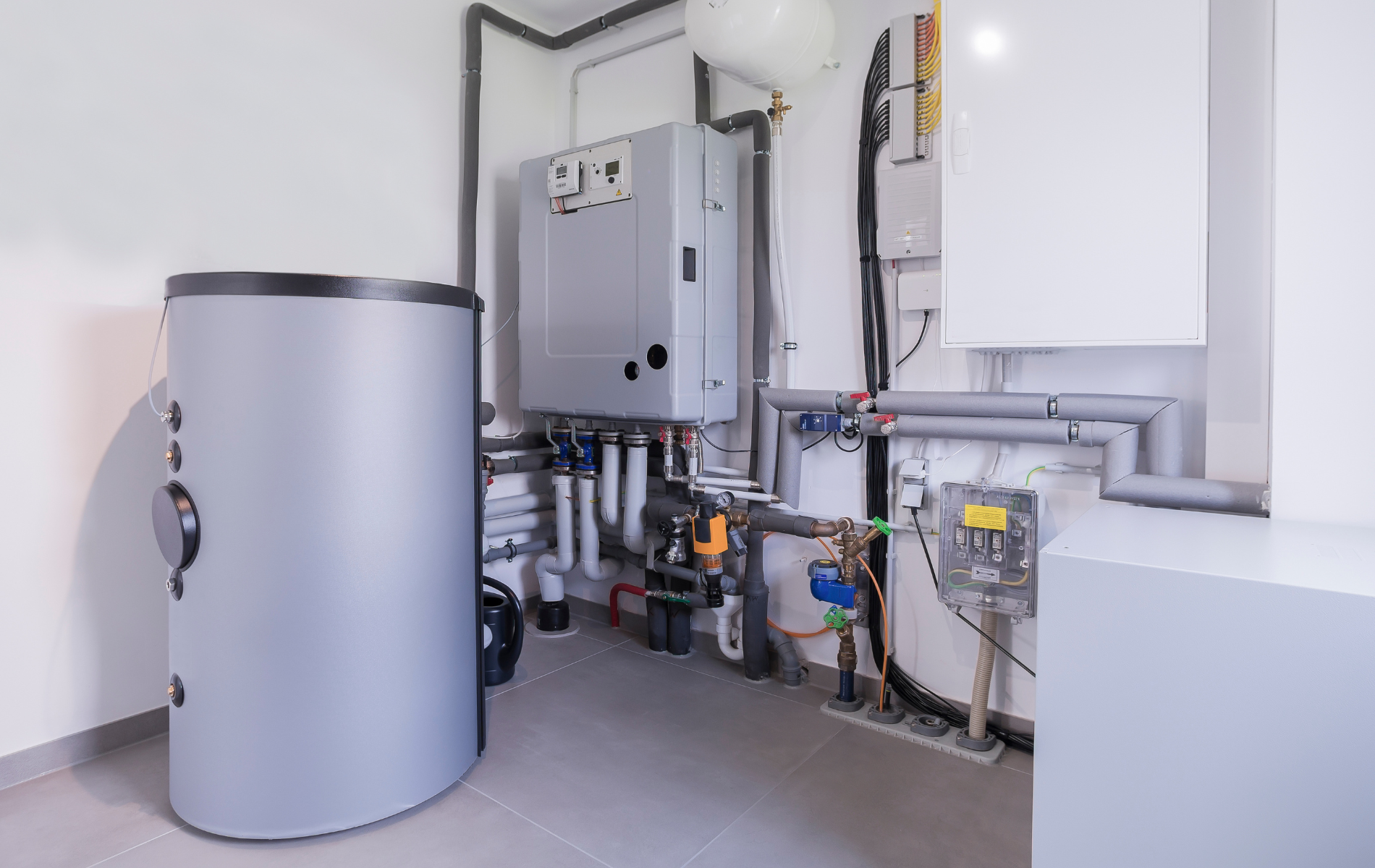A room with a water heater and a boiler in it.